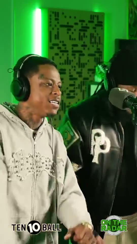 Fetty Wap and Remy Boy Monty performing 679 at a mic in a small studio booth lit green, a round neon sign on the wall